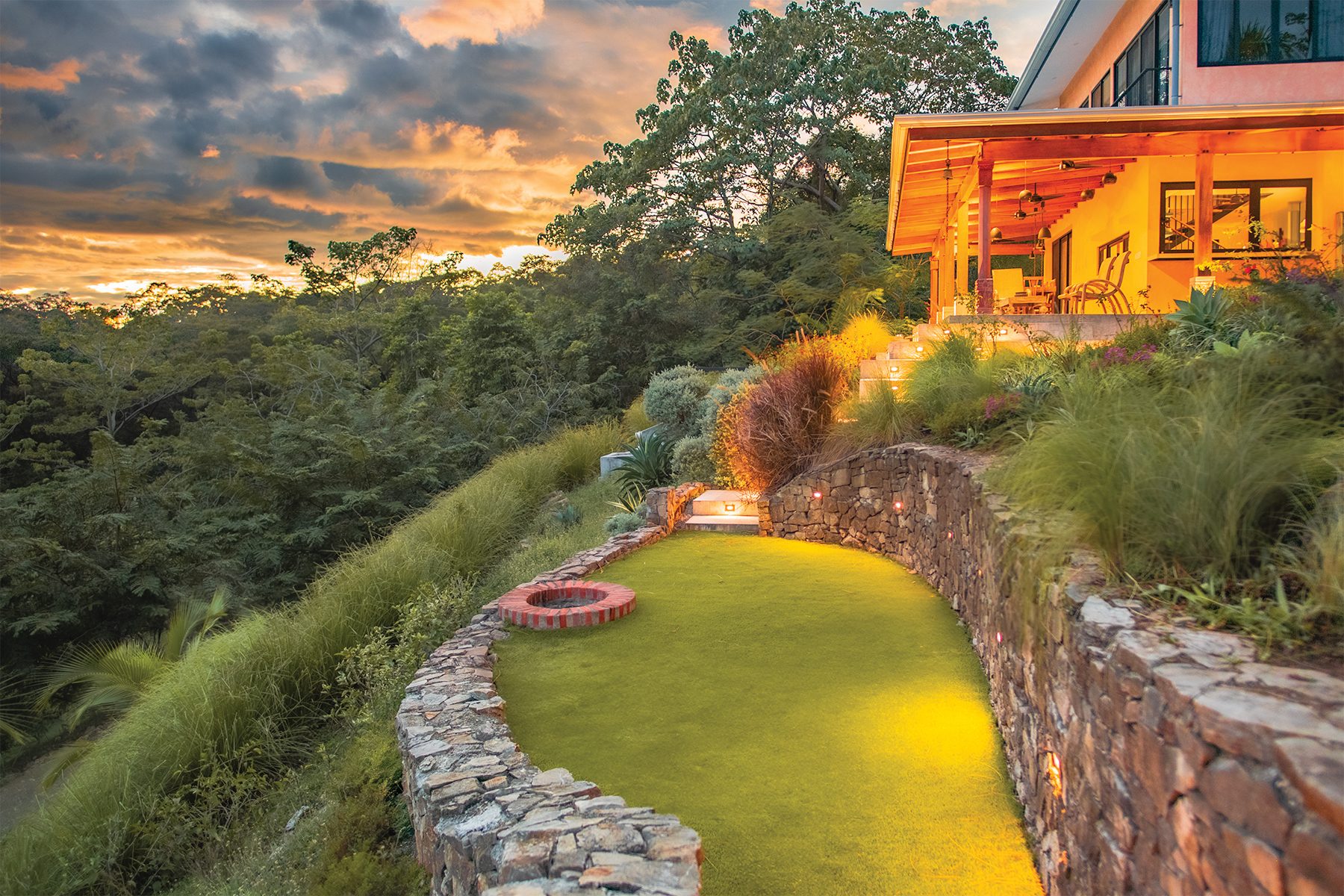 The fire pit lit at dusk below the residence