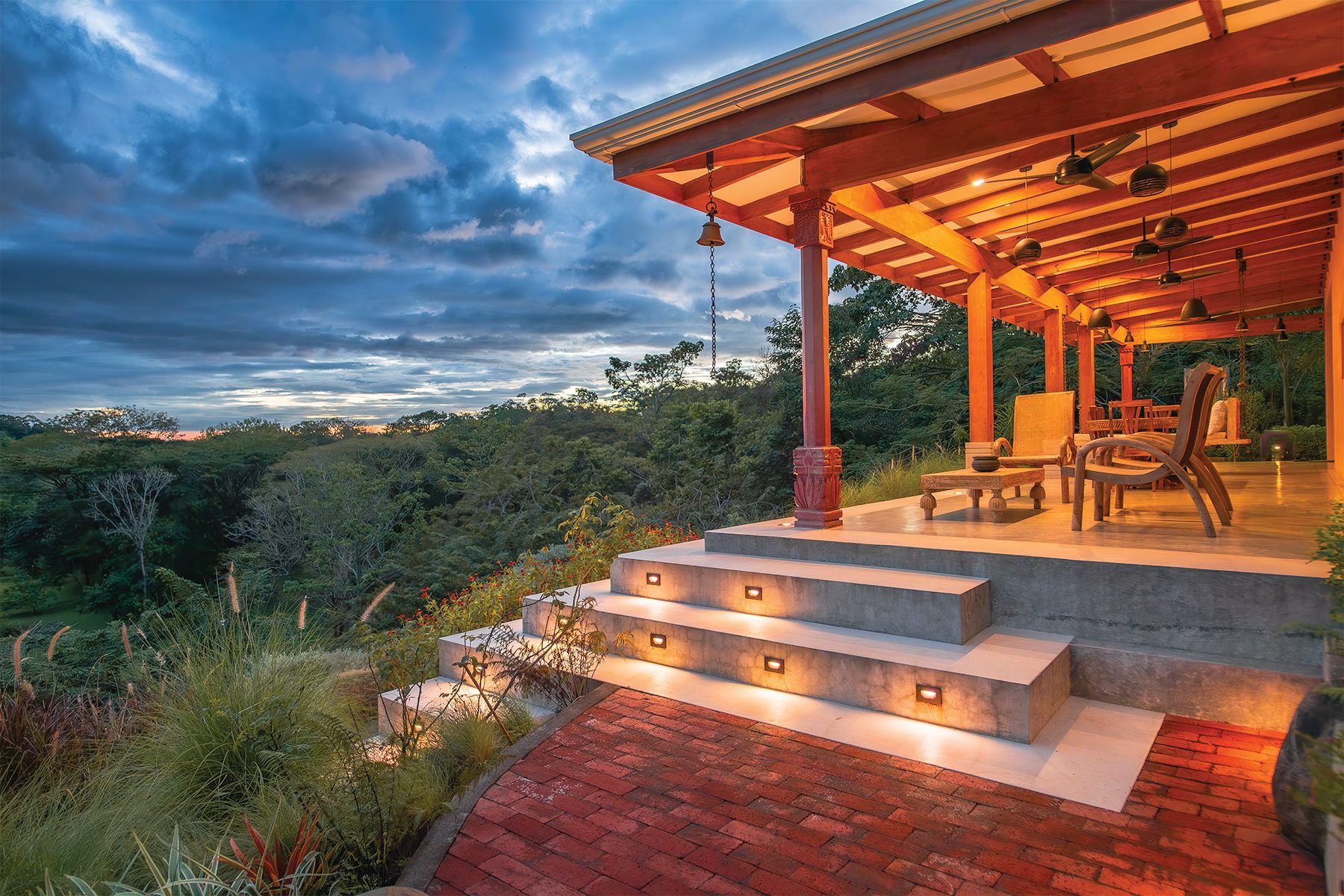 Lit stone terrace steps descending through planted gardens at dusk at The Sanctuary Estate, Nosara, Costa Rica