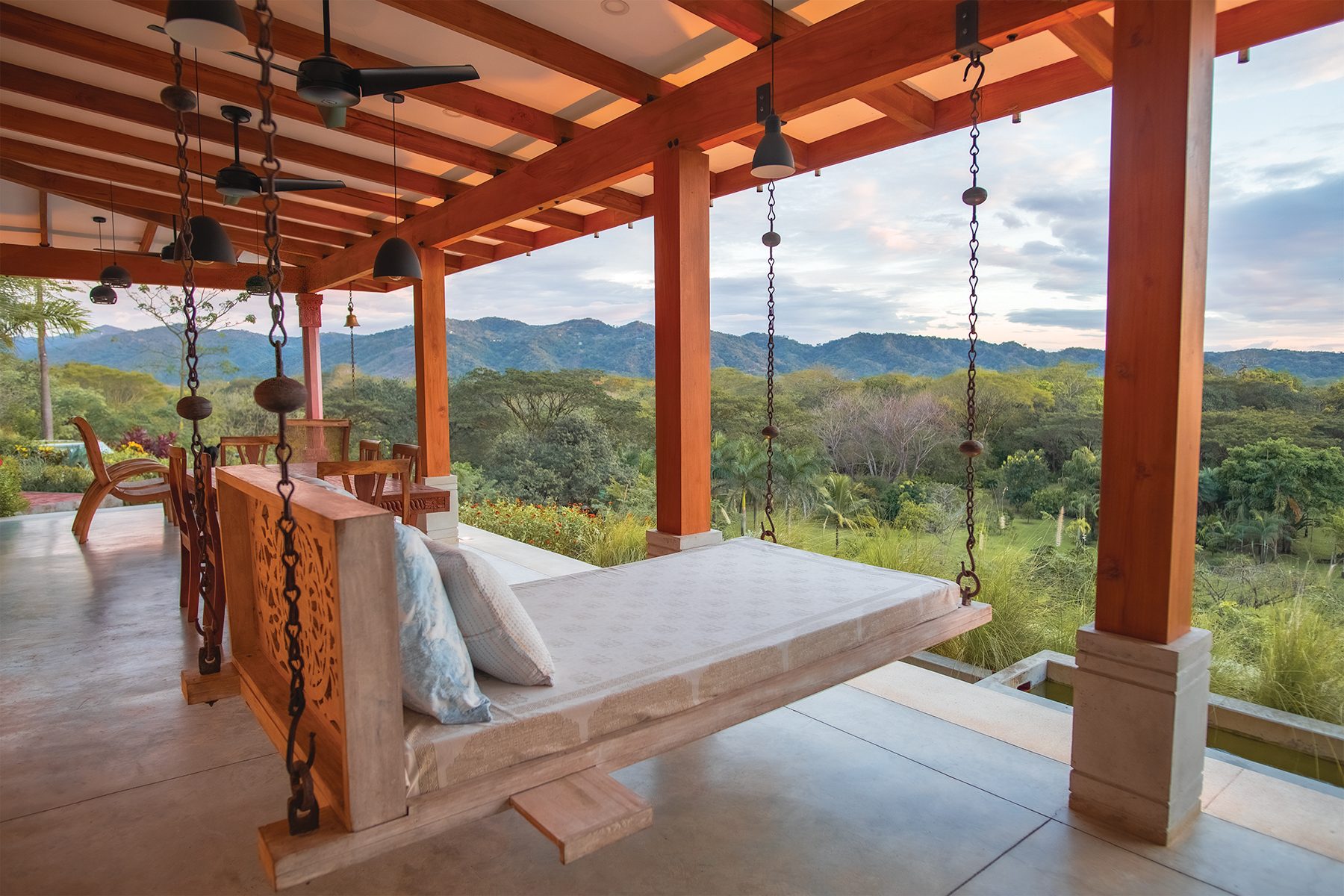 A hand-carved hanging daybed on the estate's covered veranda, overlooking the Nosara hills
