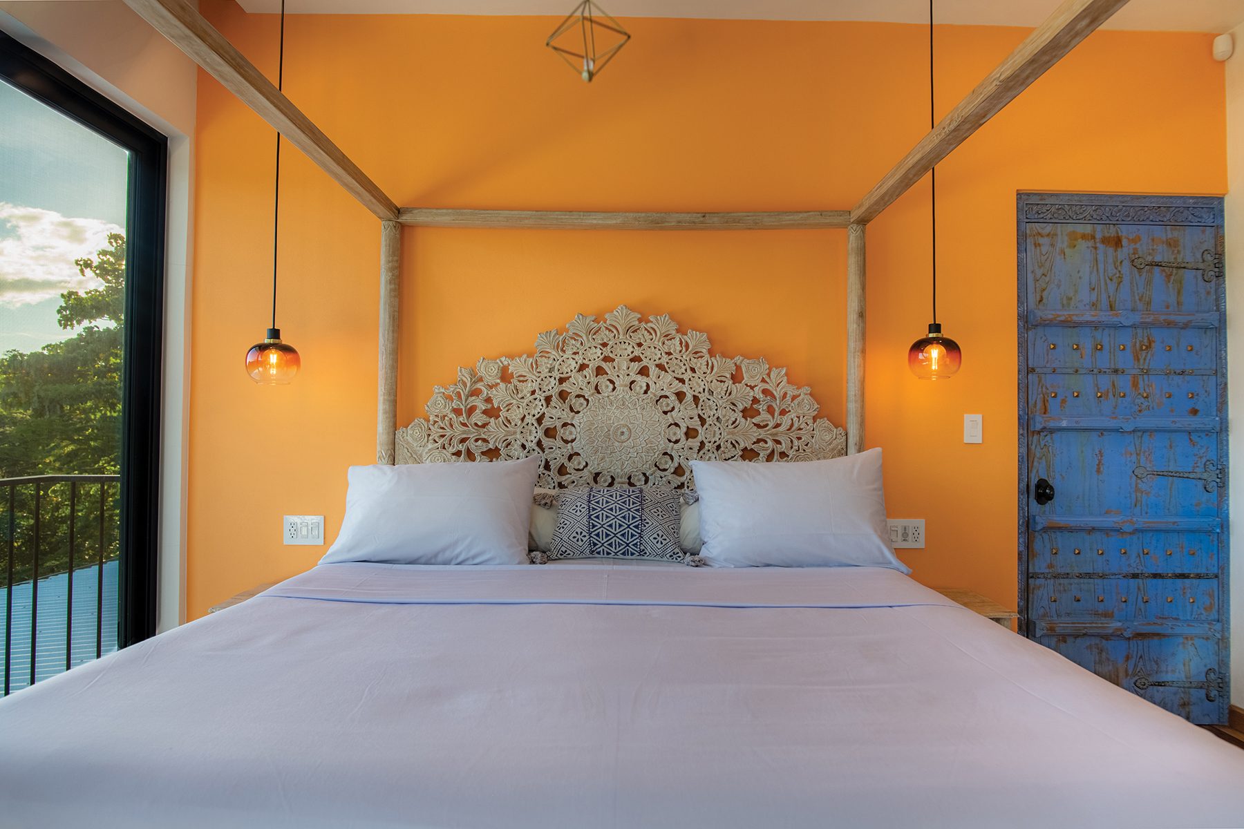 Orange bedroom carved headboard — The Sanctuary Estate, Nosara, Costa Rica