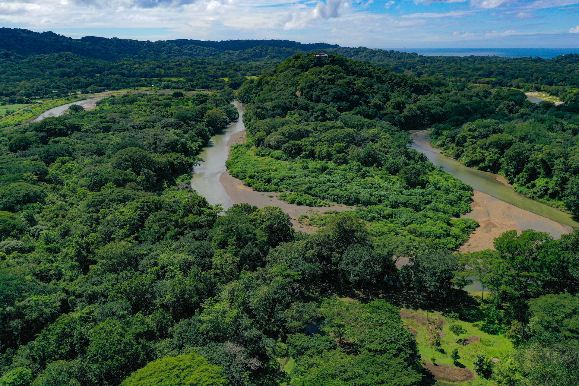Aerial view of the Nosara River meandering through unbroken forest toward the Pacific, Guanacaste, Costa Rica